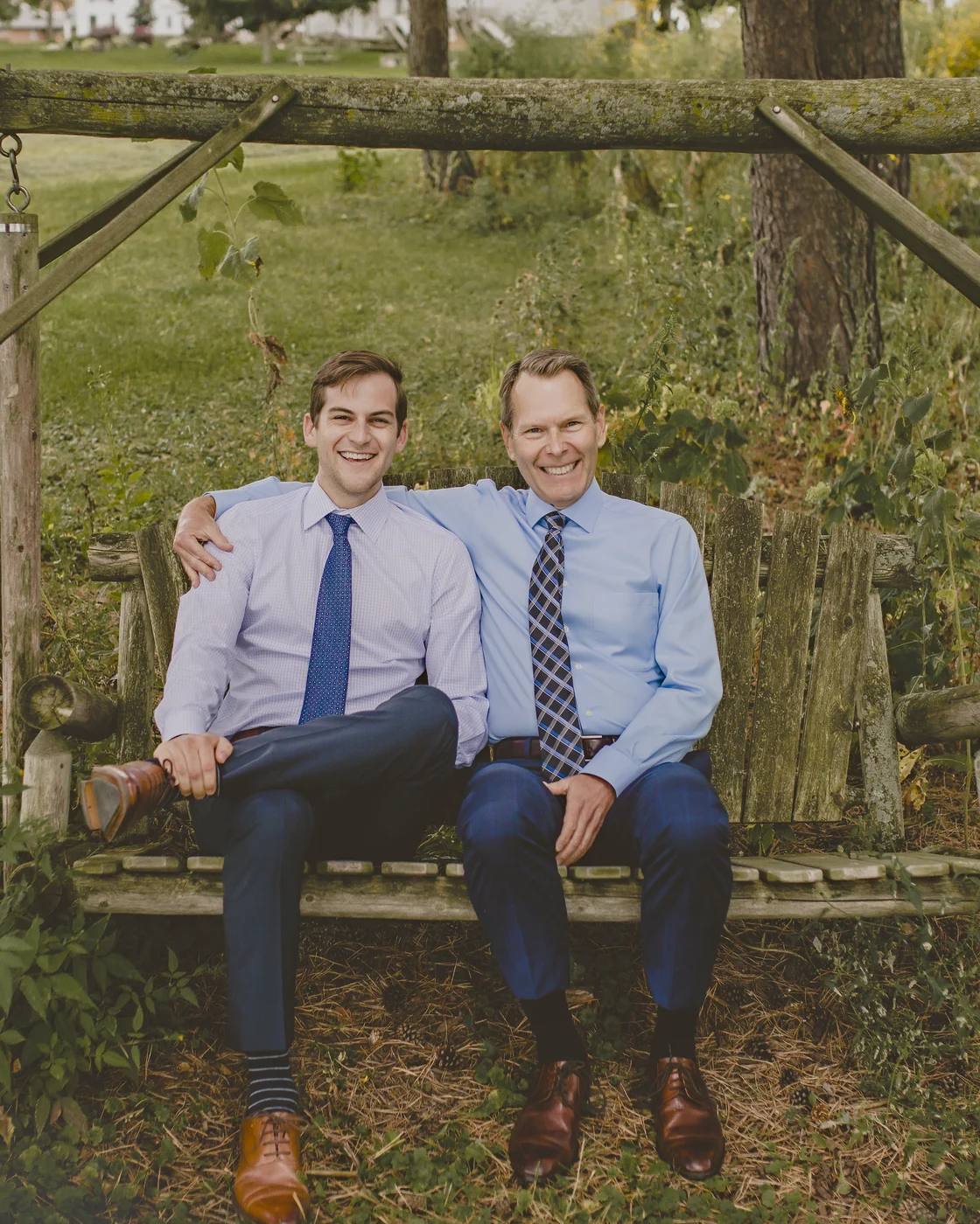 Dr. David Markiewicz and Dr. Anthony Markiewicz sitting together on a wooden swing outside